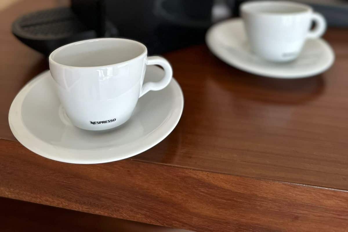 A coffee machine with two white cups on a wooden table.