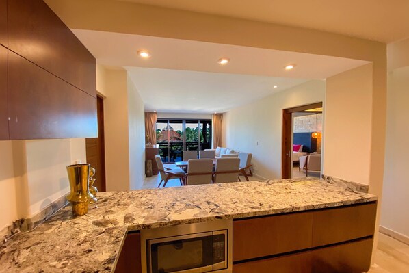 A kitchen with a granite countertop, a built-in oven, and a dining area with a table and chairs.