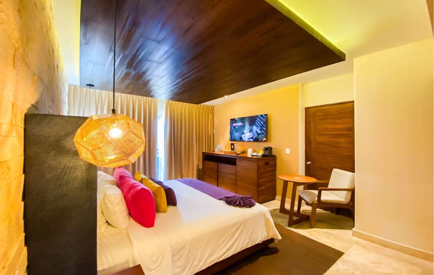 Una habitación de hotel moderna con cama, escritorio, silla y televisor.