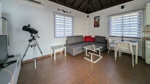 Ein Wohnzimmer mit einer Couch, einem Esstisch und einem Teleskop.
