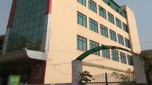 A multi-story building with a modern architectural design, featuring large windows and a prominent entrance archway. - Hotel Prakash Palace (Varanasi)