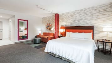 Una habitación de hotel con una cama grande, un sofá, una mesita y un espejo.