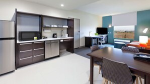 A modern kitchen with stainless steel appliances, a dining area with a table and chairs, and a view of the outdoors through a window. - Home2 Suites by Hilton Abilene (Abilene)