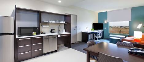 Una cocina moderna con electrodomésticos de acero inoxidable, una zona de comedor con mesa y sillas, y vistas al exterior a través de un ventanal.