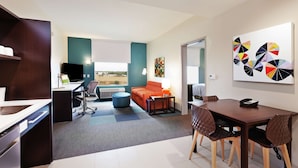A modern living room with a dining area, a kitchen, and a large window with a view. - Home2 Suites by Hilton Abilene (Abilene)