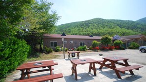 A rustic building with picnic tables and a parking area. - M Motel (Gangneung)
