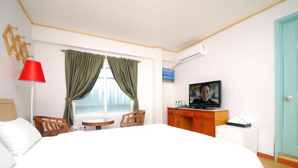 A hotel room with a large bed, a desk, a chair, a TV, and a window with curtains. - M Motel (Gangneung)