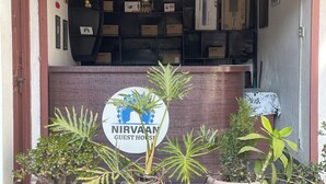 A reception area with a sign reading "NIRVANA GUEST HOUSE" and multiple potted plants in front. - Nirvaan Guest House (Kathmandu)