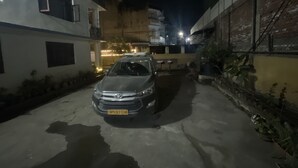 A narrow street with a parked car and buildings on either side. - Nirvaan Guest House (Kathmandu)
