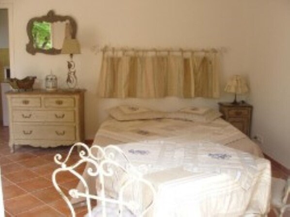 A bedroom with a bed, a dresser, a nightstand, and a mirror on the wall.