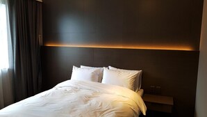 Una habitación de hotel con una cama, una mesita de noche y una lámpara fijada a la pared.