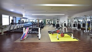 Un gimnasio con cintas de correr, máquinas de pesas y pesas libres.