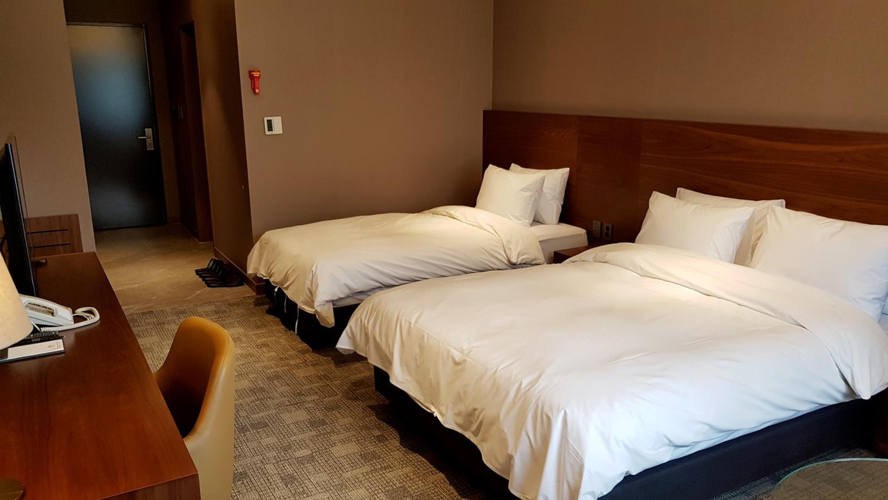 Habitación de hotel con dos camas, un escritorio con teléfono y una silla.