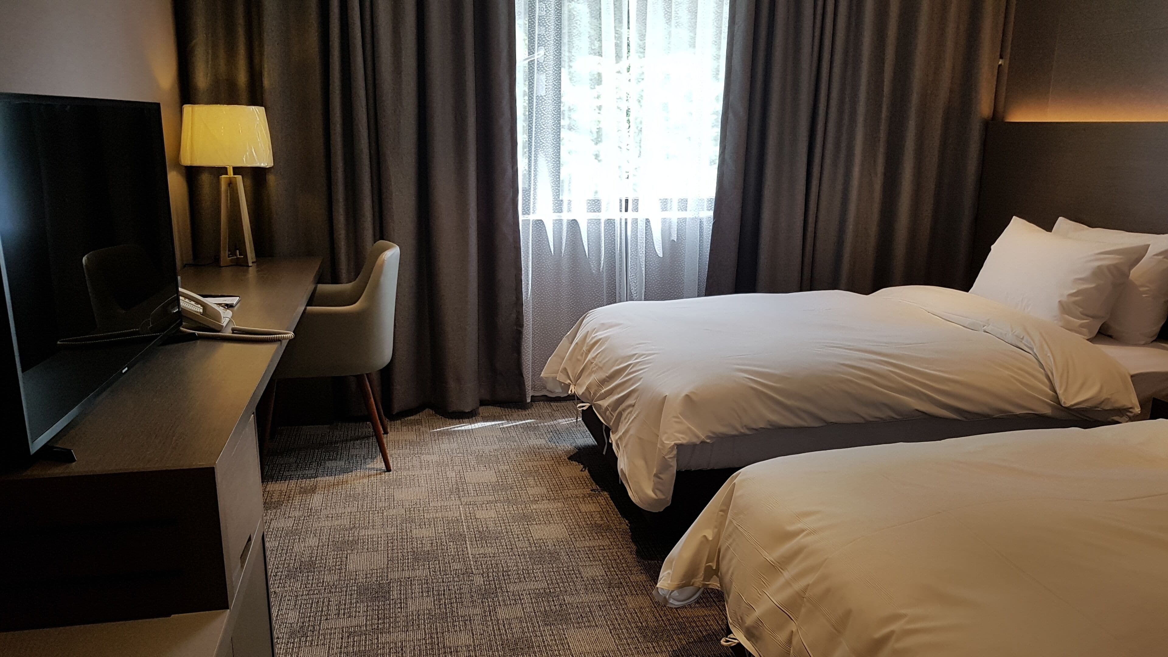 Una habitación de hotel con televisión, escritorio, silla y dos camas.
