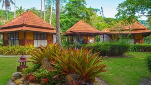 A traditional-style building with a tiled roof, surrounded by lush greenery and a well-maintained garden with rocks and plants. - Ko Kut Ao Phrao Beach Resort (Ko Kood)