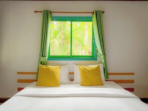 A bed with white bedding and two yellow pillows, a window with green curtains, and a view of greenery outside. - Ko Kut Ao Phrao Beach Resort (Ko Kood)