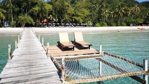 A wooden pier leading to a beach with lounge chairs and a netted area. - Ko Kut Ao Phrao Beach Resort (Ko Kood)