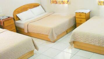 A room with two beds, wooden headboards, a nightstand, and a small dresser.