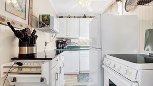A compact kitchen with white cabinets, a built-in oven, and a coffee maker.