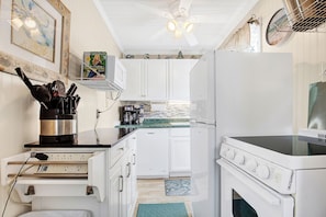 Compact kitchen with modern design, equipped with a dishwasher, stove, and microwave, plus a ceiling fan for ventilation and additional storage.