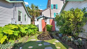 A residential area with two houses, a garden with stepping stones, and a palm tree.