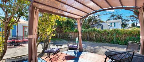 Relax in a serene outdoor space surrounded by lush greenery and a shaded pergola.