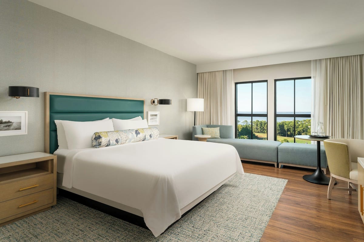 Une chambre d’hôtel avec un grand lit, un canapé, un bureau et une vue sur l’extérieur.
