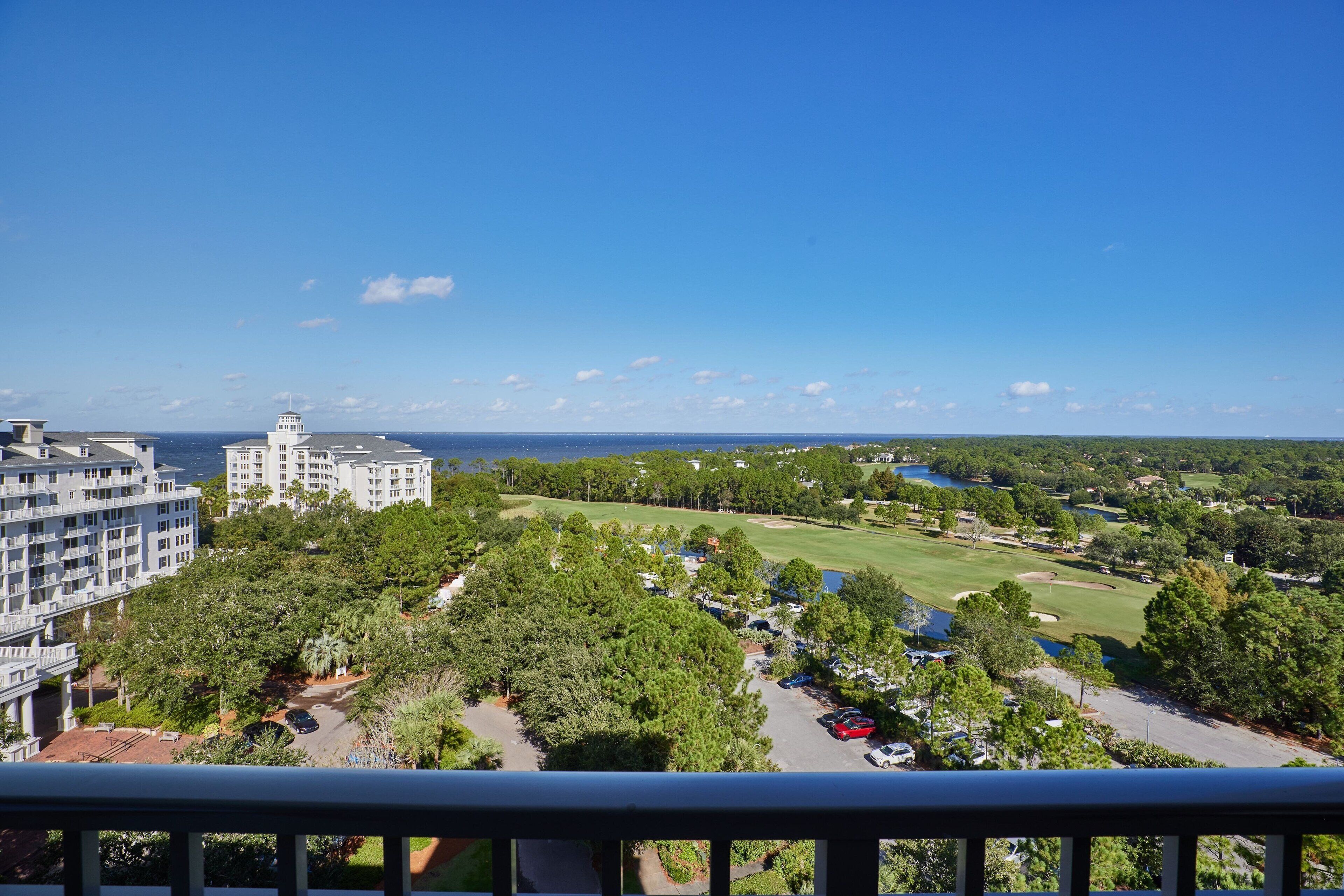 A residential area with a view of a golf course, a body of water, and a distant lighthouse.