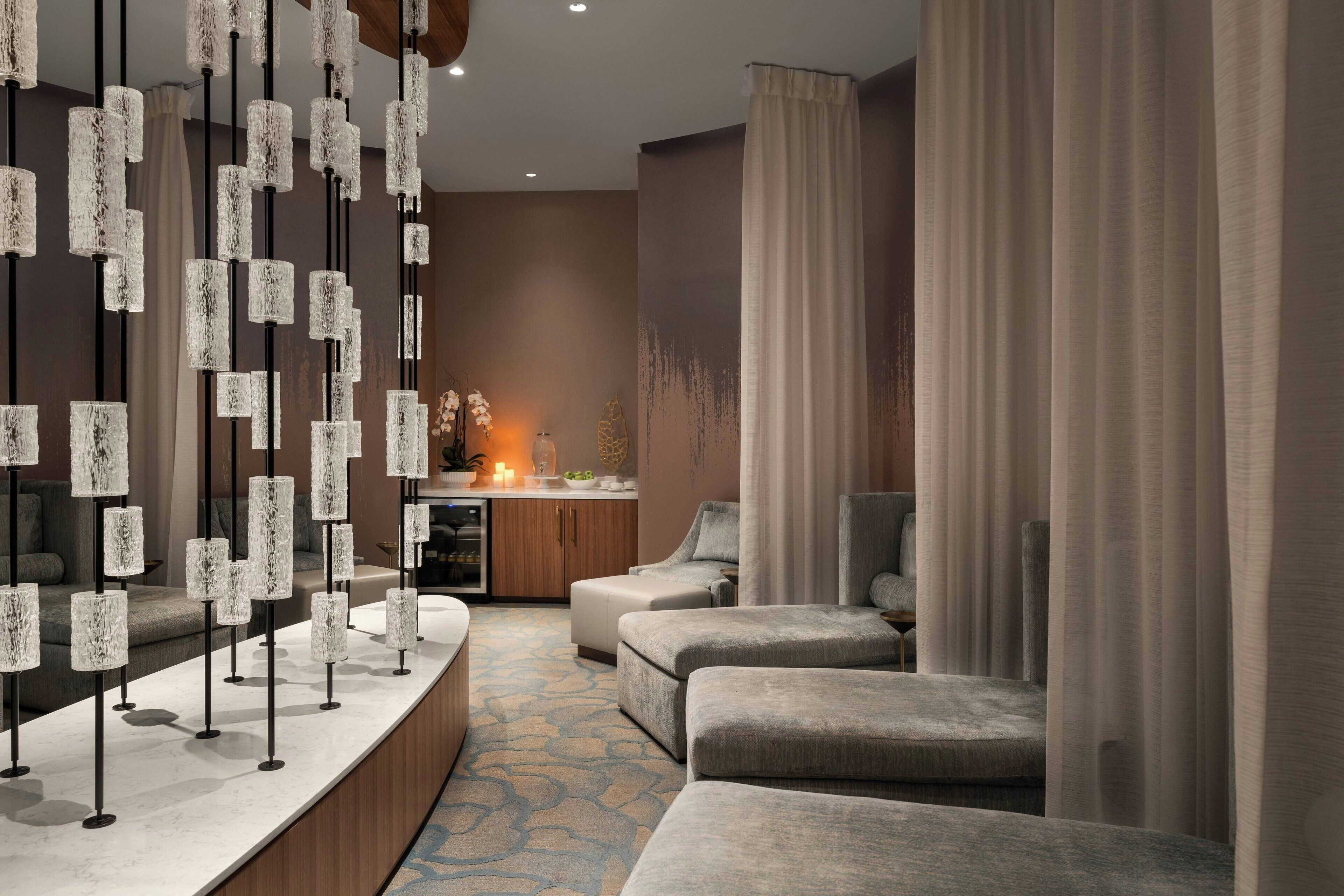 A modern room with a long counter, multiple seating areas, and a decorative light fixture.