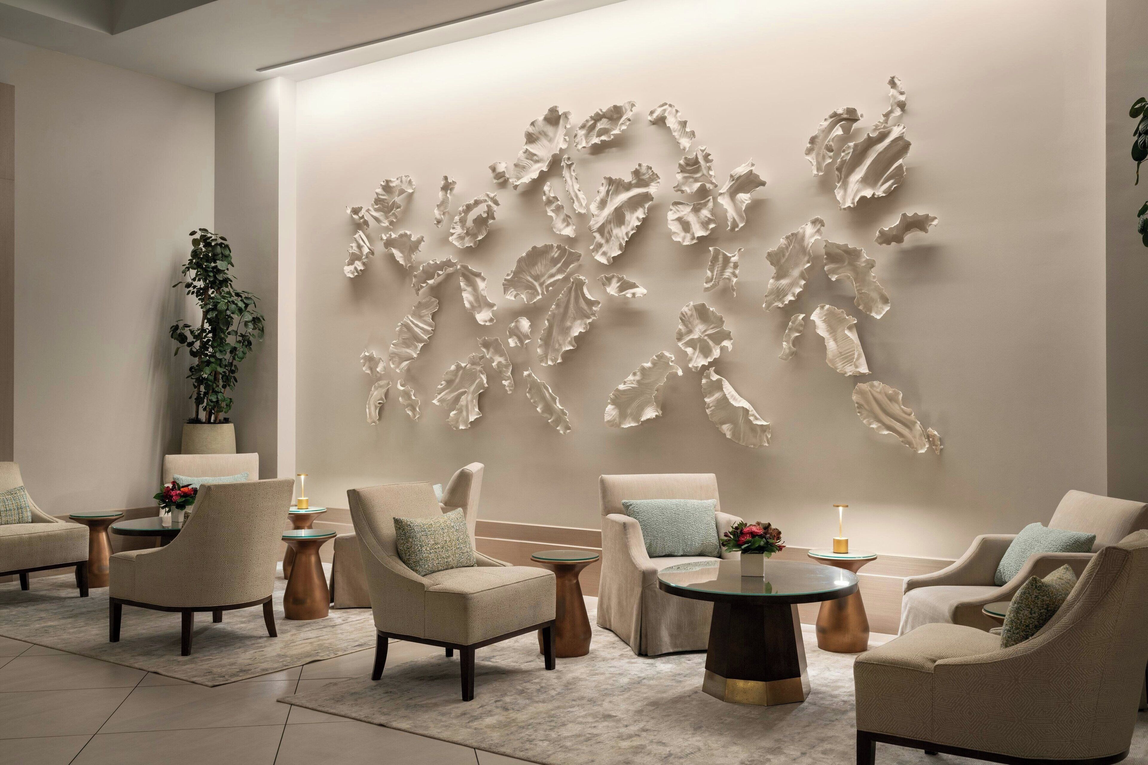 A modern lounge area with sofas, a coffee table, and a decorative wall piece.
