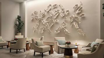 A modern lounge area with sofas, a coffee table, and a decorative wall piece.