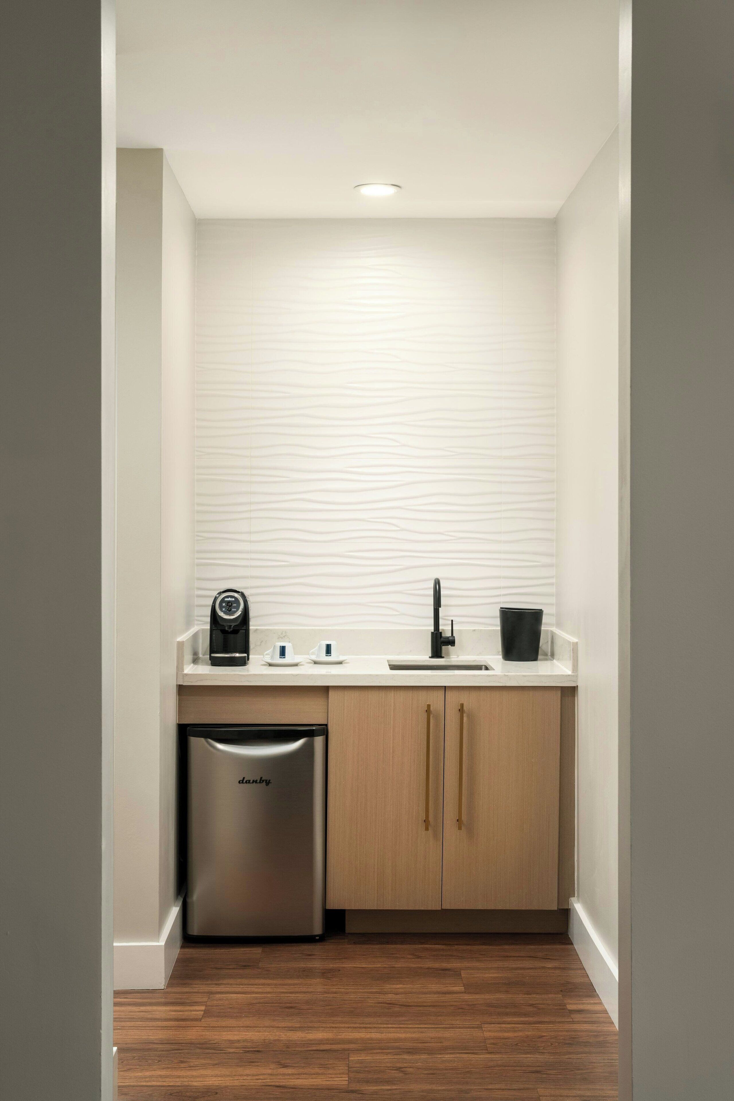 A compact kitchen with a built-in dishwasher, a sink, and wooden cabinets.