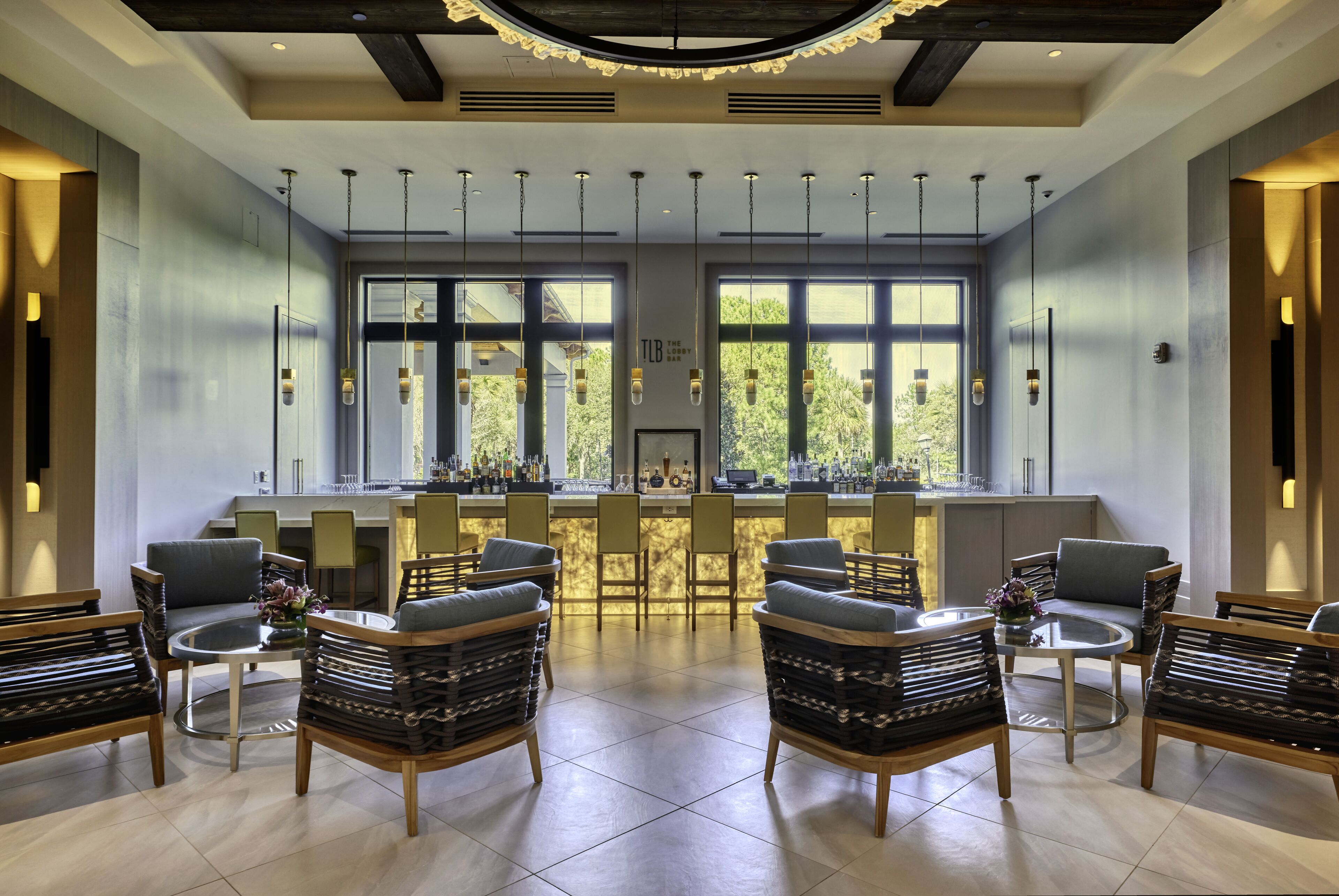 A spacious bar area with multiple seating options, including bar stools and chairs, and large windows providing natural light.