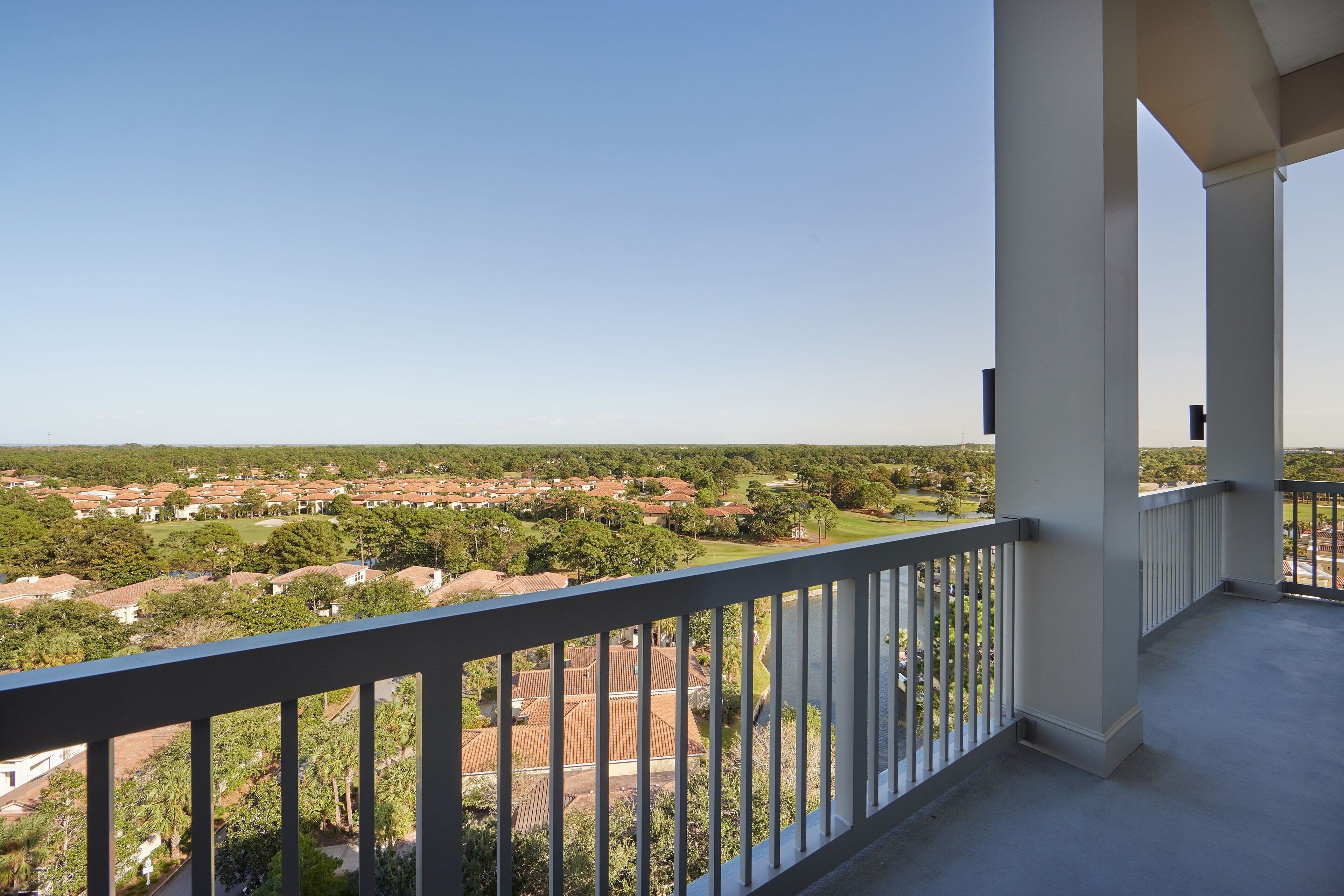 A balcony with a view of a residential area, featuring houses and greenery.