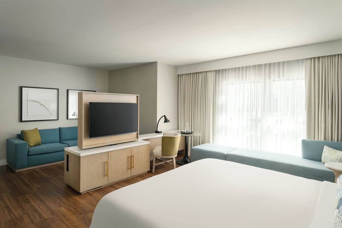 Une chambre d’hôtel avec un grand lit, une télévision, un canapé, un bureau et une chaise.