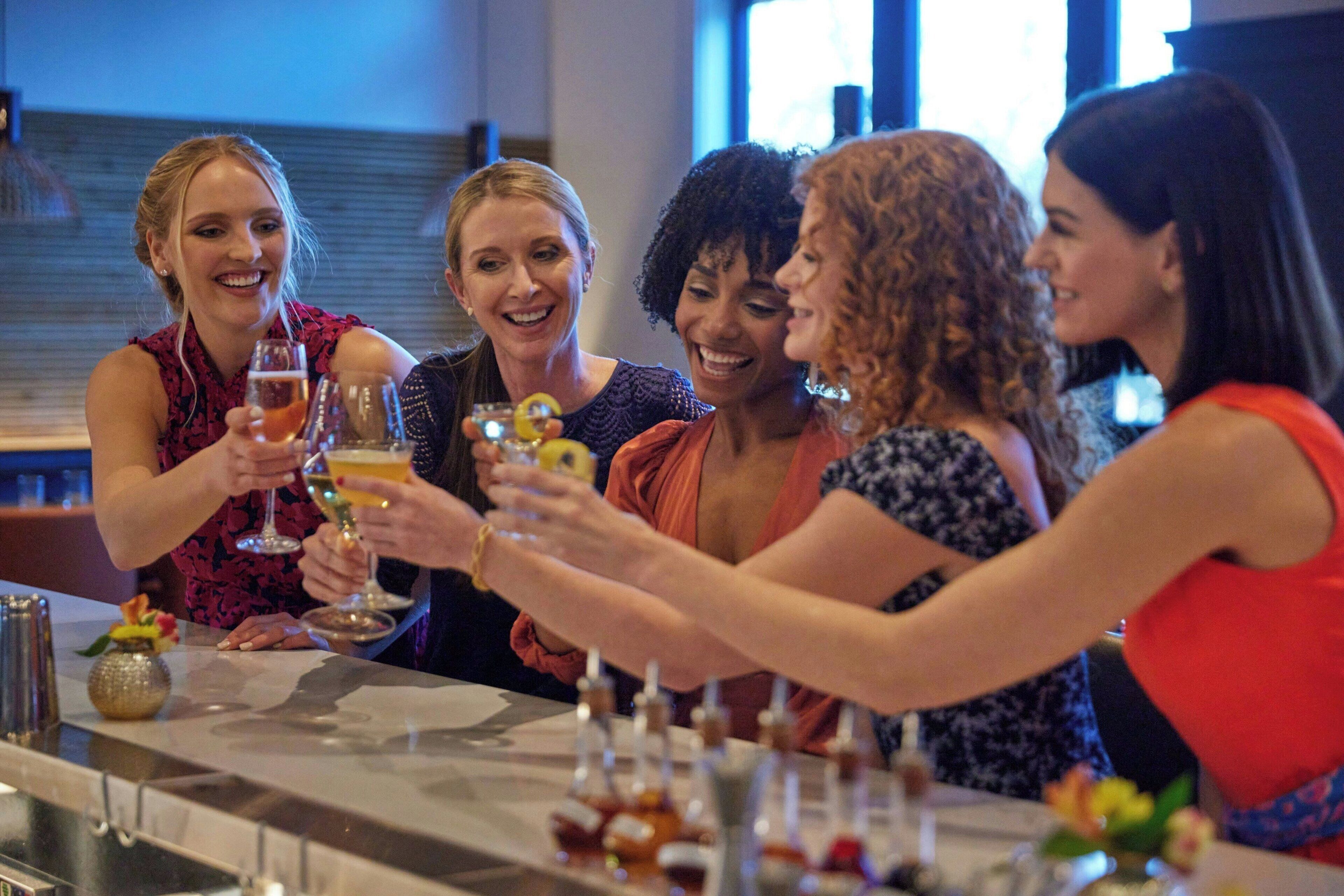 Un groupe de personnes trinquant avec des boissons dans un bar, des bouteilles et des verres étant posés sur le comptoir.