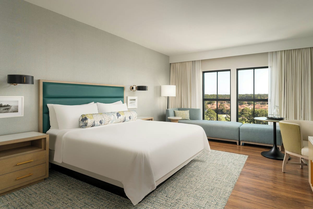 Une chambre d’hôtel avec un grand lit, un canapé, un bureau et une vue sur la ville.