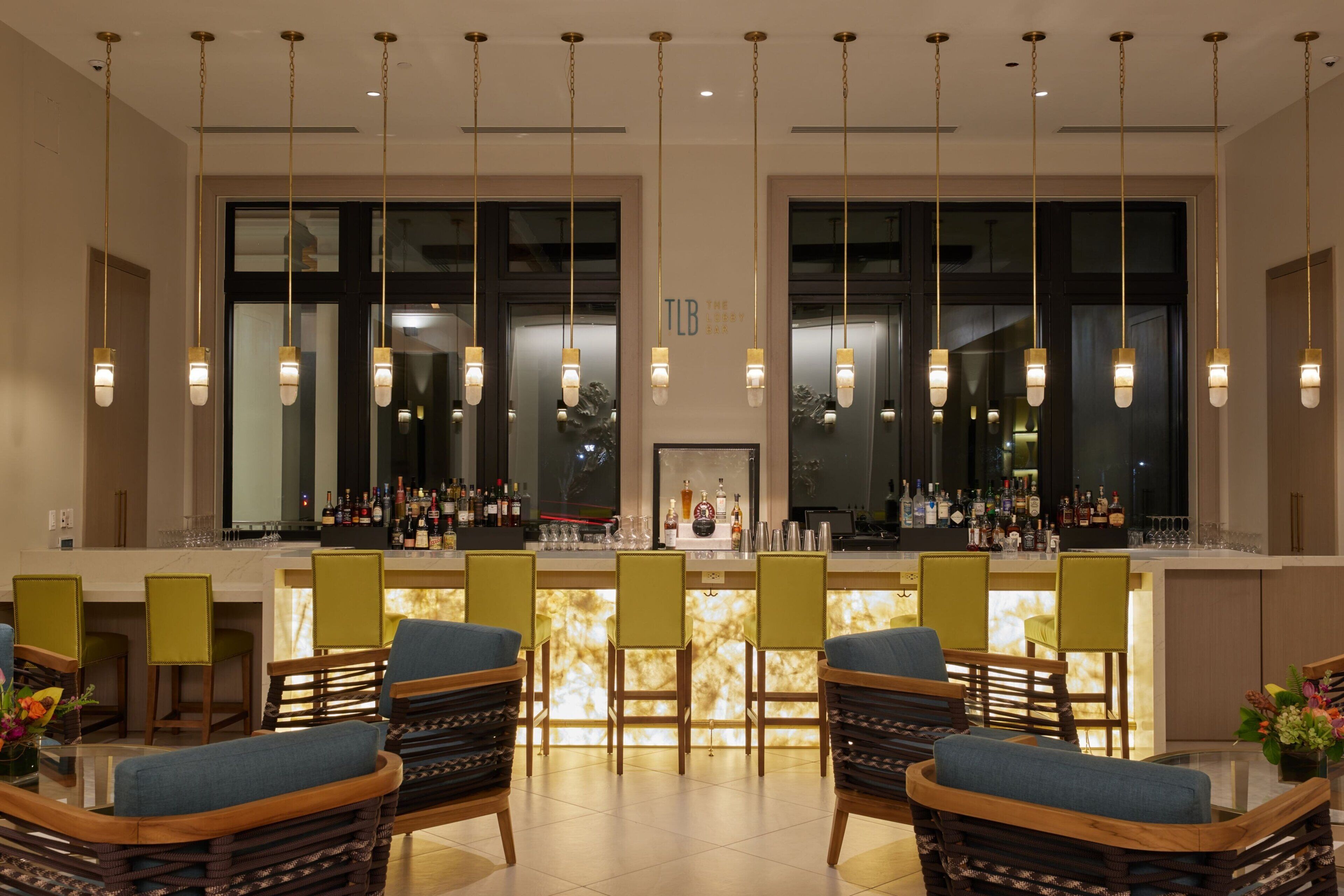 A bar area with a counter, multiple chairs, and hanging pendant lights.