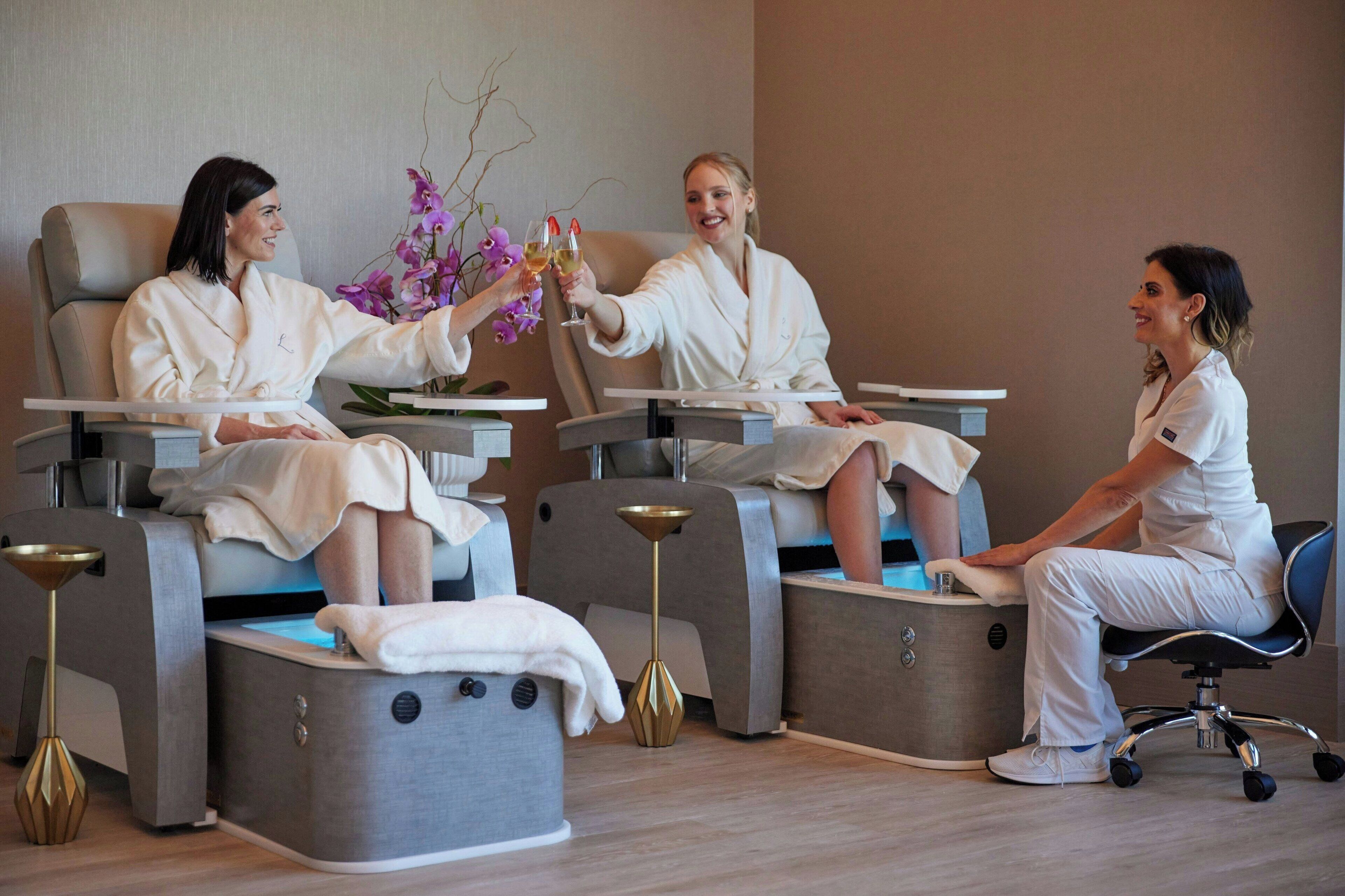 A modern spa with three clients seated in individual chairs, each with a footrest and a small table.