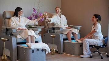 A modern spa with three clients seated in individual chairs, each with a footrest and a small table.