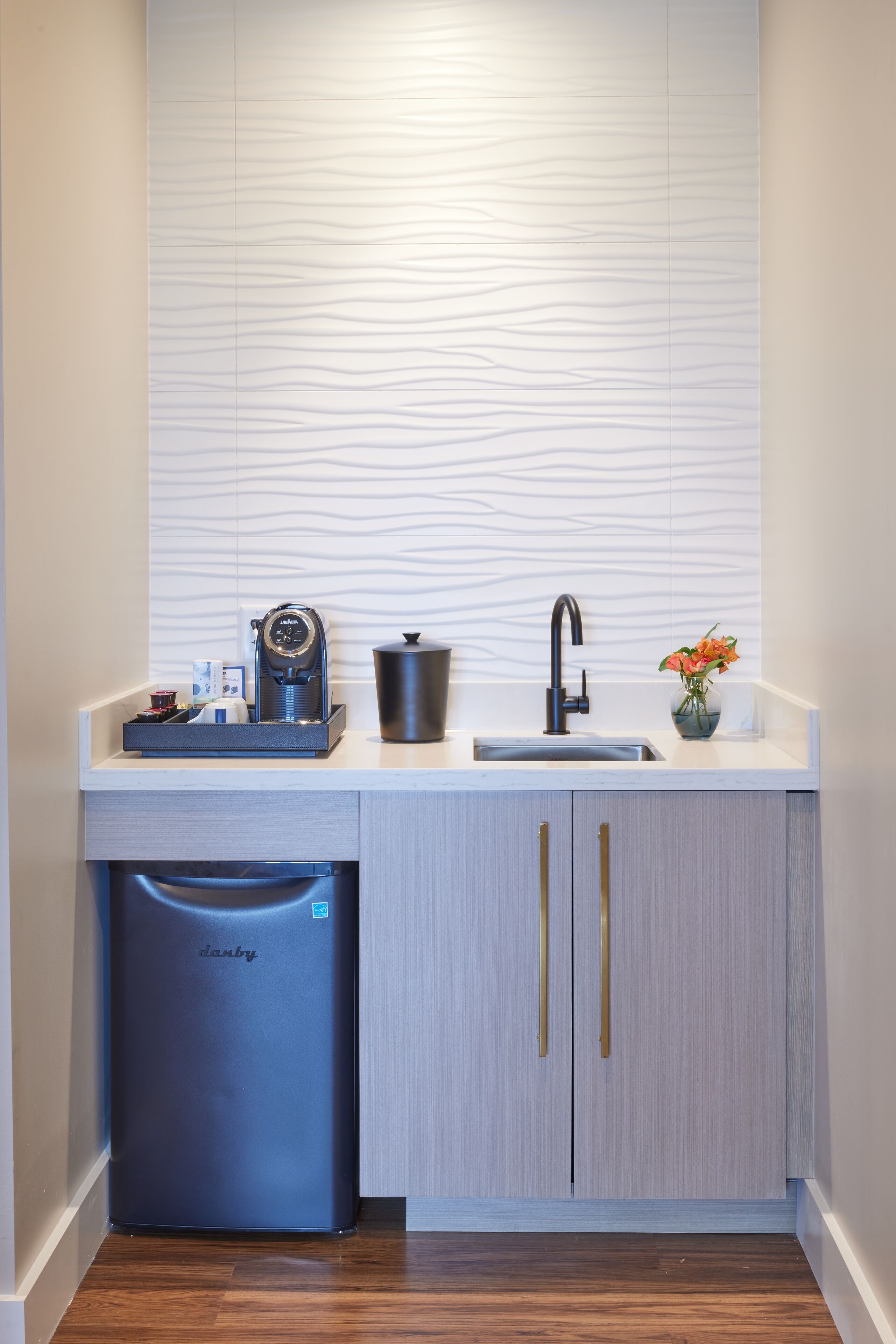A compact kitchen with a coffee machine, a sink, and a dishwasher.