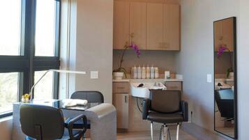 A modern hair salon with two chairs, a large mirror, and a circular light fixture.
