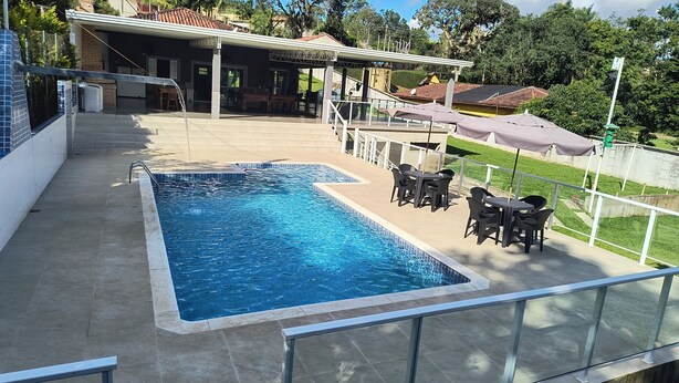 A swimming pool with a patio area, outdoor seating, and a covered structure. - Beautiful farm with swimming pool, a small island. Near the Rio Jaguari Waterfall. (Extrema)
