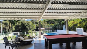 An outdoor pool area with a red pool table, lounge chairs, and a view of the surrounding greenery. - Beautiful farm with swimming pool, a small island. Near the Rio Jaguari Waterfall. (Extrema)