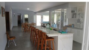 A spacious kitchen with a long counter, wooden stools, and a view to the outside. - Beautiful farm with swimming pool, a small island. Near the Rio Jaguari Waterfall. (Extrema)