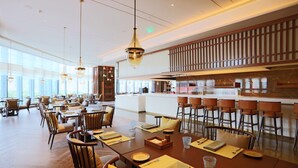 A spacious dining area with high ceilings, modern lighting, and a central bar area.