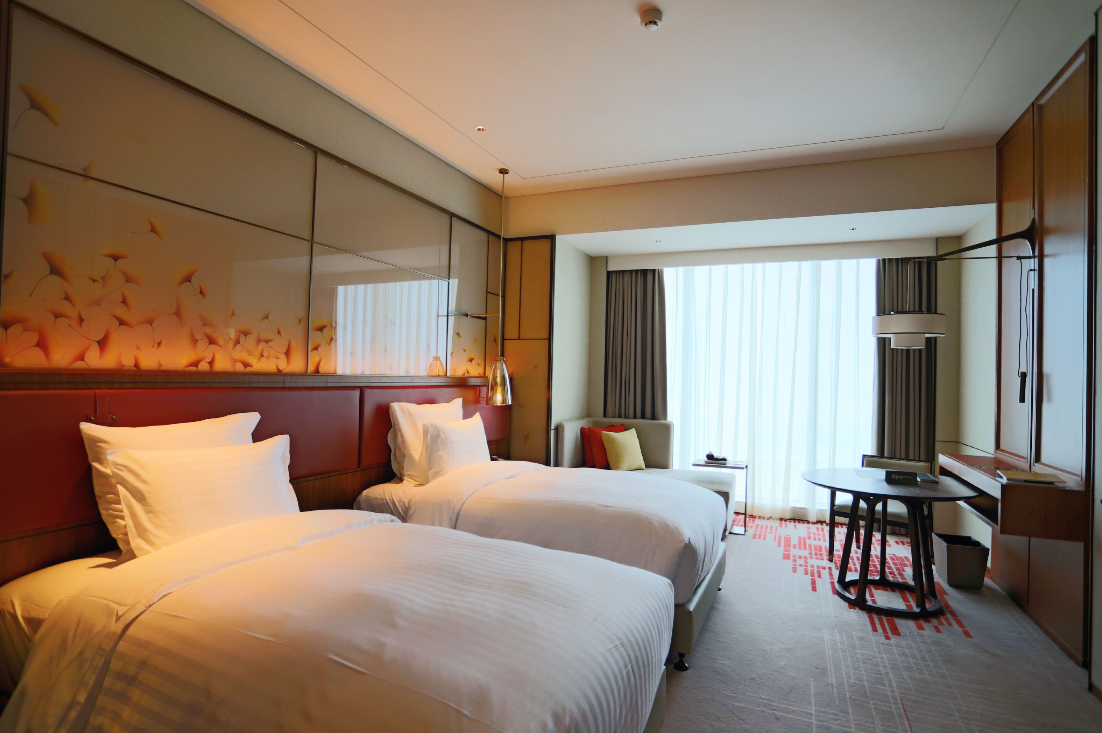 Een hotelkamer met twee bedden, een bureau en een stoel.