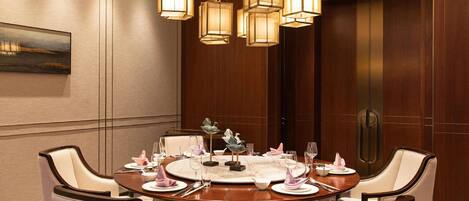 A dining room with a round table, chairs, and hanging pendant lights.
