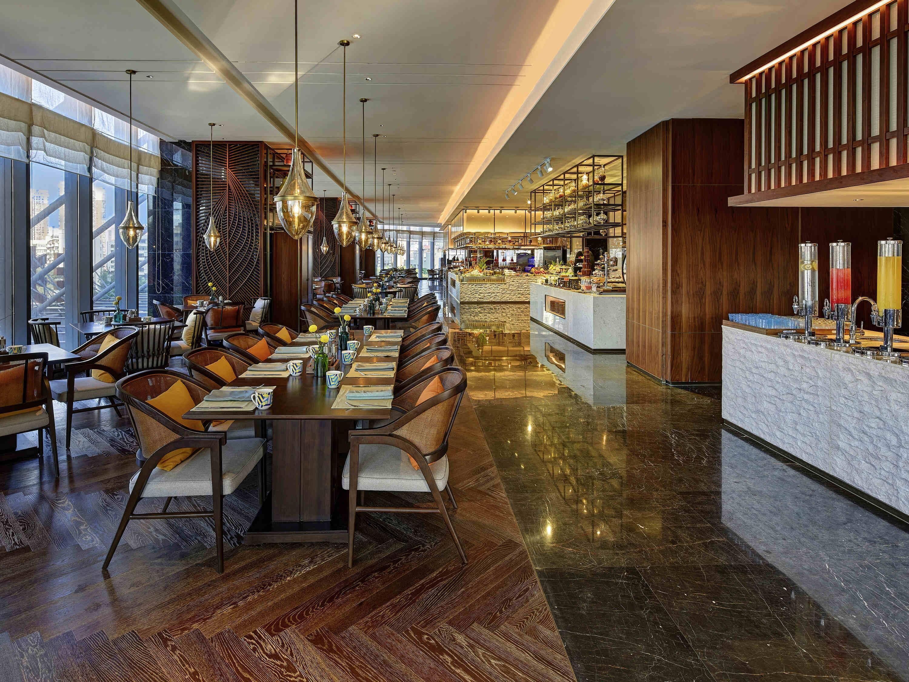 Ein modernes Restaurant mit hohen Decken, großen Fenstern und einer zentralen Bar.