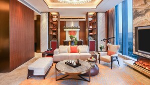 A modern living room with a fireplace, a large chandelier, and a city view.